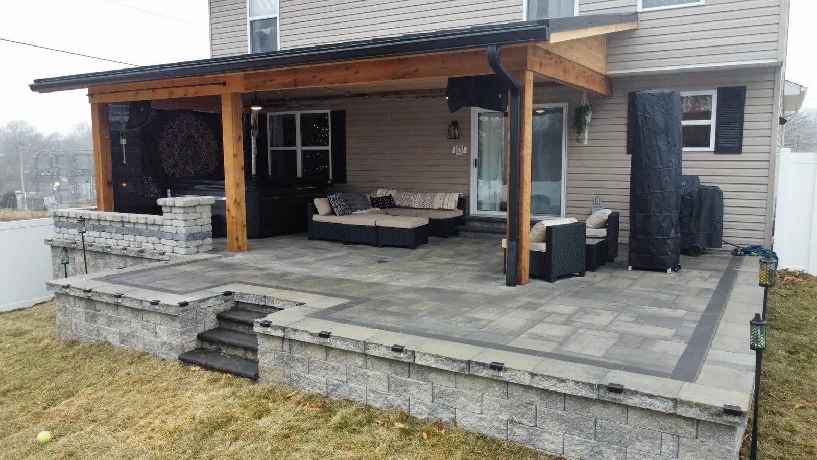 Covered outdoor living area with custom pavers and seating in St. Louis