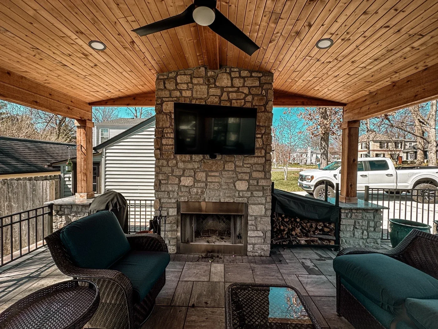 Covered outdoor fireplace and stone entertaining space by STL Hardscape Solutions in West County