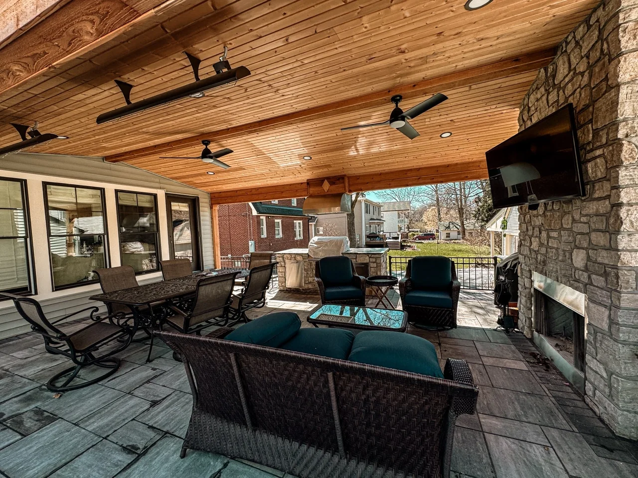 Covered outdoor living room with stone fireplace and timber ceiling in St. Louis
