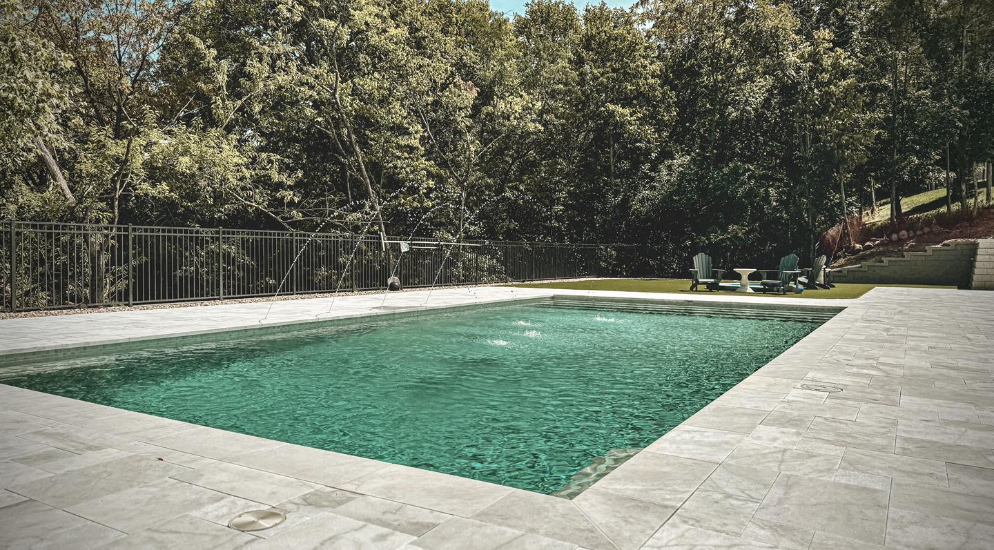 Custom pool patio with paver surround and wooded backdrop in St. Louis